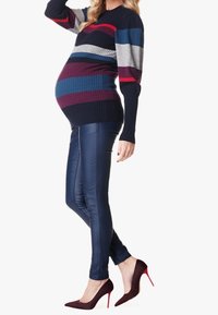 Jersey de maternidad con rayas en azul marino, gris y burdeos; textura acanalada. Combinado con pantalones brillantes en azul marino y zapatos de tacón en burdeos.