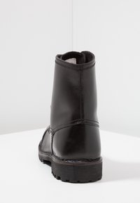 Botte cheville en cuir noir avec une texture lisse, bout arrondi, talon renforcé et semelle en caoutchouc avec un motif de bande de roulement texturé.