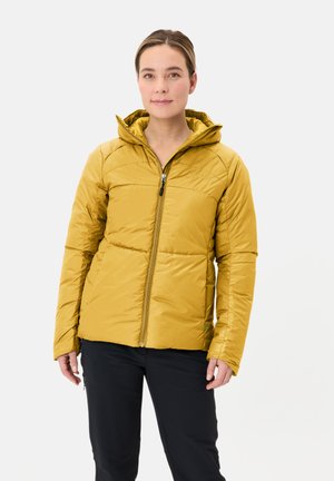 Gelbe isolierte Jacke mit Kapuze, seitlichen Reißverschlusstaschen und gesteppter Optik. Glatte Textur und körpernahe Passform. Getragen mit schwarzen Hosen.
