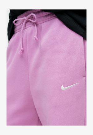 Roosad Nike dressipüksid, millel on nööriga vöökoht ja väike valge logo küljes, valmistatud pehmest ja tekstuurse materjaliga.