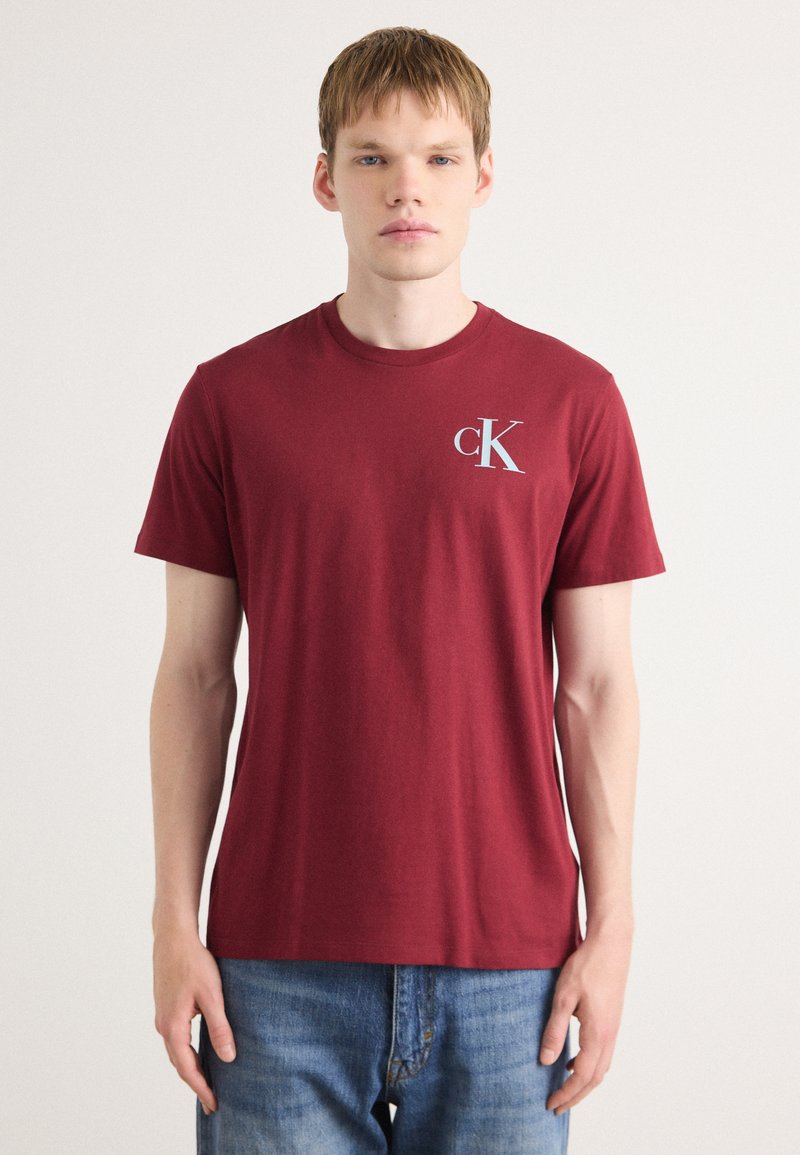 Bordó T-shirt, pamutből készült, kereknyakú, bal mellen egy kis fehér "cK" logóval, rövid ujjú.