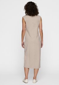 Vestito beige senza maniche con una silhouette aderente e dettagli sulla cucitura posteriore, che si estende fino al polpaccio, realizzato in un tessuto morbido e elastico.