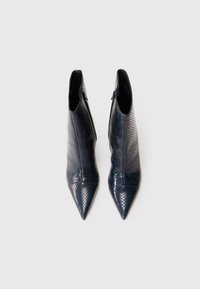 Botines de tacón puntiagudo, realizados en imitación de piel de serpiente azul marino, con un diseño elegante y cierre de cremallera lateral para facilitar su uso.