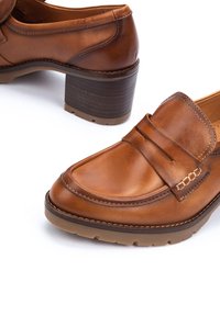 Chaussures mocassins pour femmes en cuir marron avec talons épais, bouts arrondis et détails cousus sur semelles et brides.