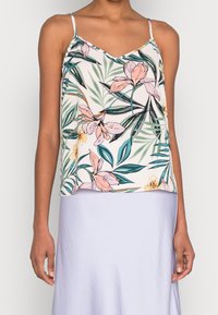 Haut sans manches à motif floral en tissu doux, présentant un col en V, des motifs floraux roses et verts sur un fond pâle, avec des bretelles fines et réglables.