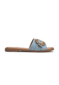 Sandalo in denim azzurro chiaro con suola piatta, caratterizzato da un dettaglio circolare in tonalità dorata sulla fascia superiore. Texture liscia e design aperto.
