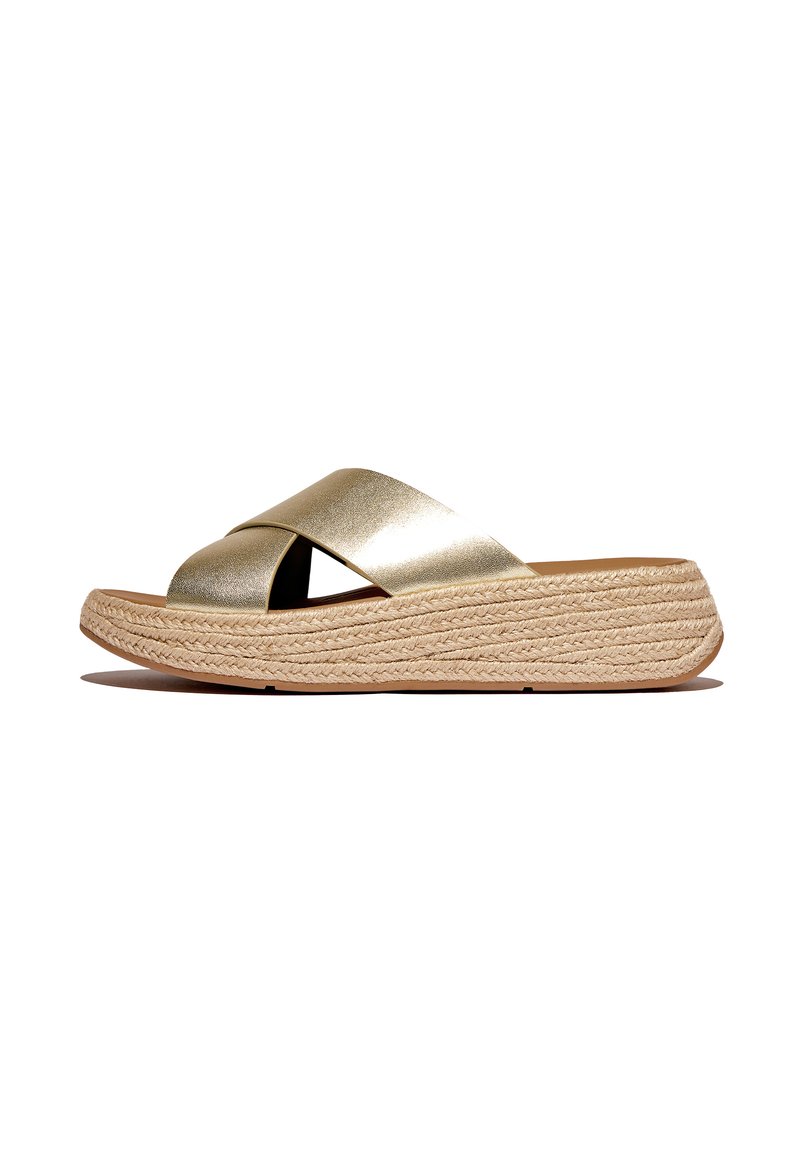 Gouden metallic slide-sandalen hebben een brede cross-strap ontwerp, een met jute omhulde platformzool en een gladde, textuur bovenkant.