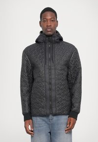 Schwarze steppjacke aus glänzendem material mit einer kordelzugkapuze, ausgestattet mit einem durchgehenden reißverschluss und einem kontrastierenden strukturierten muster.