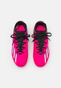 Scarpette da calcio rosa con una tomaia testurizzata, lacci neri e tre strisce bianche sui lati. Design leggero per maggiore agilità.