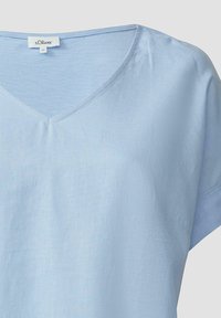 Himmelblaues V-Ausschnitt-T-Shirt aus weichem Stoff. Es hat kurze Ärmel und eine lockere Passform mit minimaler Textur. Das Etikett zeigt den Markennamen und die Größe an.
