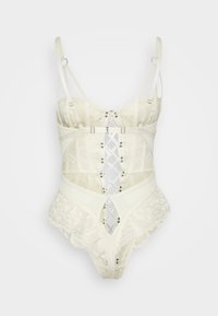 Witte kanten bodysuit met verstelbare bandjes, uitsnijdingen en decoratieve hardware. Bevat florale kantafwerking langs de randen.