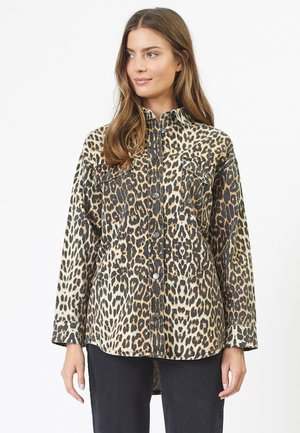 Chemise en imprimé léopard beige et noir, en denim, à manches longues, avec une fermeture à boutons sur le devant, deux poches poitrine, coupe décontractée, ourlet arrondi.