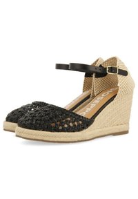 Chaussures compensées espadrilles noires en toile tissée avec une semelle en jute, dotées d'une sangle noire à la cheville et d'une partie supérieure texturée beige.