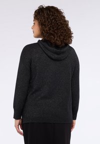 Felpa con cappuccio nera con una finitura testurizzata e scintillante. Presenta una vestibilità comoda, maniche lunghe e un cappuccio morbido e fluente. Design semplice, senza motivi visibili.