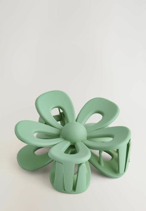 Roheline lillekujuline juukseklamber, millel on väljalõigatud kroonlehed ja ümar keskus, valmistatud pehmest plastmassist ning omab tekstureeritud mati viimistlust.