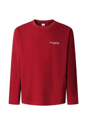 Czerwona koszula z długim rękawem wykonana z miękkiej tkaniny. Posiada okrągły dekolt i biały nadruk z napisem na lewej stronie klatki piersiowej. Prosty fason, bez dodatkowych ozdób.