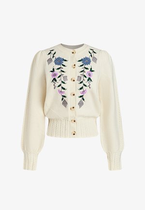 Cardigan color crema con ricami floreali in blu e viola, bottoni dorati e orlo a trecce testurizzato; maniche lunghe a sbuffo.