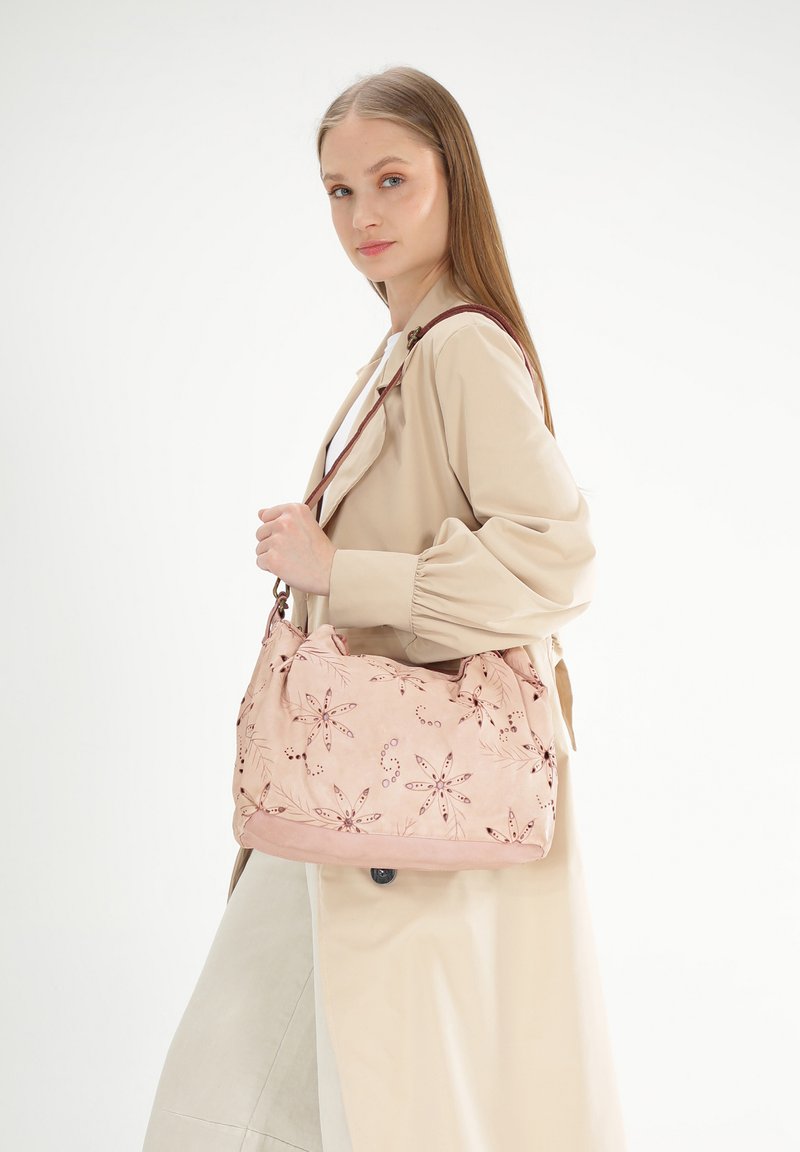 Hellrosa Stoff-Schultertasche mit floraler Stickerei, weicher Textur und strukturiertem Design. Enthält einen braunen Riemen und subtile Akzente.