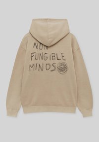 Beżowa bluza z dużym, ręcznie napisanym napisem "NIE FUNGOWALNE UMYSŁY" oraz okrągłym rysunkiem na plecach. Miękka bawełniana tkanina, casualowy design.