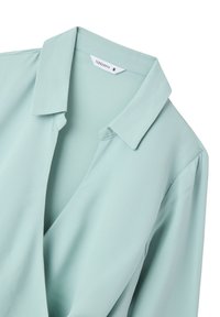 Una blusa verde menta chiaro con colletto e scollatura a V profonda. Realizzata in un tessuto morbido e leggero. Etichetta che riporta "Terranova", taglia S.