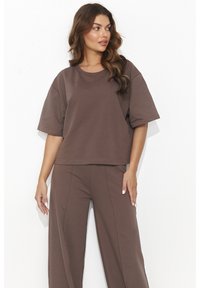 Brązowy, oversize'owy t-shirt z bawełny z krótkimi rękawami i okrągłym dekoltem, zestawiony z dopasowanymi, luźnymi spodniami z przodu z detalami szwów.