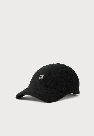 Casquette de baseball noire à la texture marquée, avec une visière incurvée et un petit logo HUGO blanc, sur fond clair.