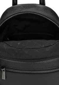 Wnętrze czarnego skórzanego plecaka z pikowaną podszewką, wyposażone w kieszeń na suwak i gładkie zamknięcie na zamek błyskawiczny. Teksturowana powierzchnia zewnętrzna.