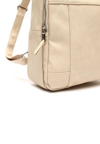 Bežinė odinė petinė rankinė su struktūruotu paviršiumi, užtrauktuku, ir subtiliais siuvinėjimo detalėmis. Reguliuojama juostelė universalumui.