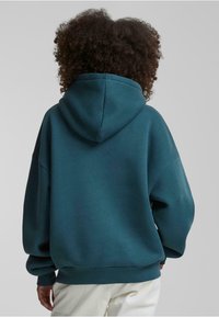 Teal oversized hoodie med en stor hætte, ribbede manchetter og kant. Blød tekstur, afslappet pasform og ingen synlige grafik eller mønstre.