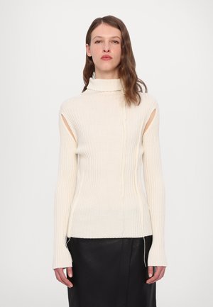 Pull en maille côtelée crème avec découpes latérales ouvertes et manches allongées, présentant un design en tricot texturé et un ourlet droit.