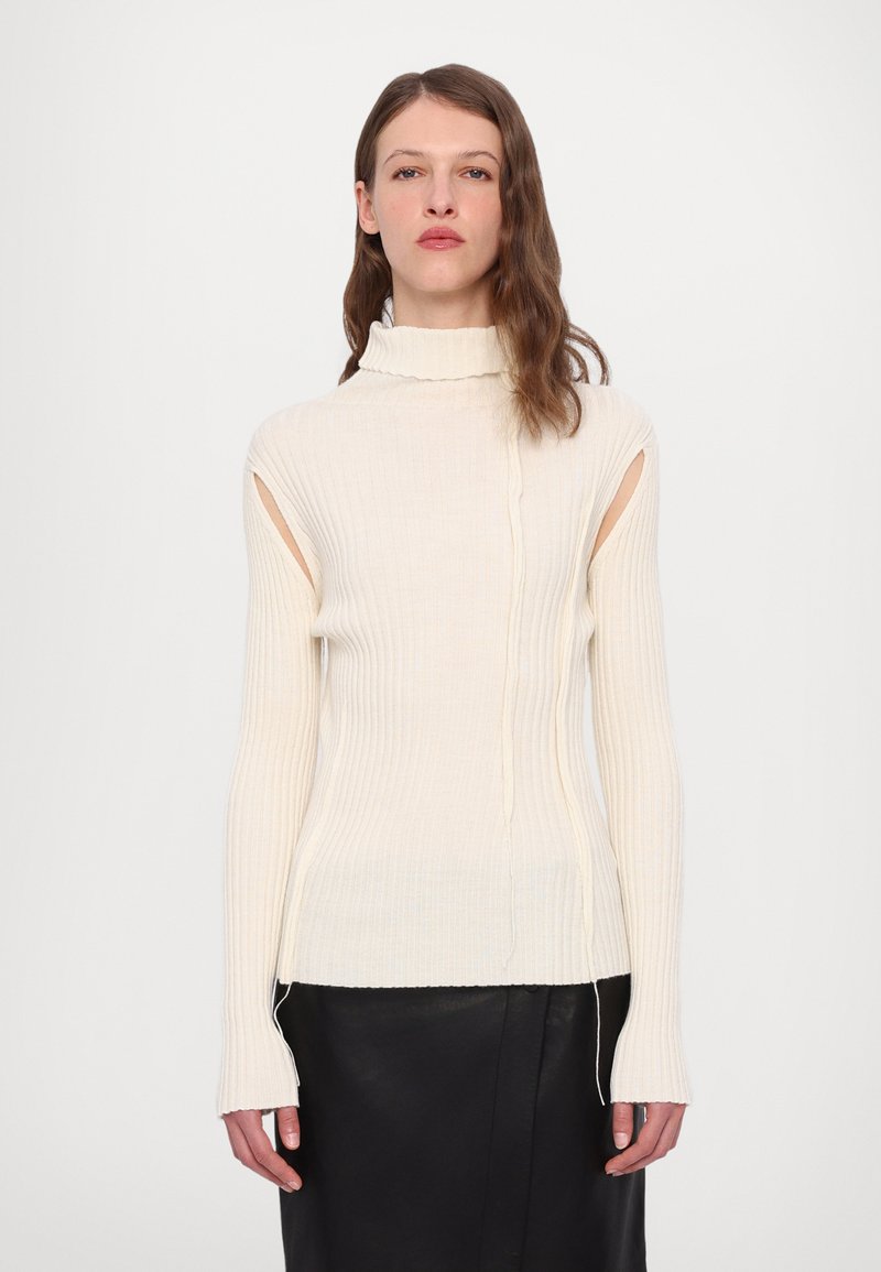 Kreem ribaga turtleneck sviiter avatud külje lõigetega ja pikendatud varrukatega, millel on tekstuuriga kudumine ja sirge äär.