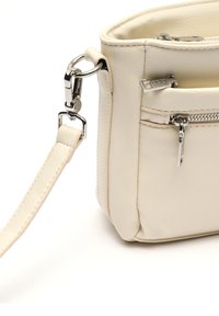 Borsa a mano in pelle beige con una forma strutturata, caratterizzata da una zip e componenti in argento, e una tracolla regolabile per maggiore versatilità.