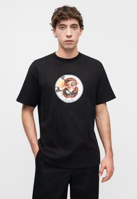 Μαύρο βαμβακερό T-shirt με κεντρικό στρογγυλό γραφικό που απεικονίζει χταπόδι, λεμόνι και πράσινες λεπτομέρειες, με κοντά μανίκια και κλασική εφαρμογή.