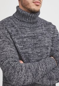 Dunkelgrauer Strickrollkragenpullover mit einem strukturierten Muster, ausgestattet mit einem hohen Kragen und gerippten Bündchen für eine enge Passform.