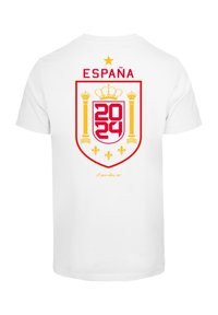 Hvid t-shirt med et rødt og gult skjolddesign, hvor "ESPAÑA" står øverst, året "2024" og et kronsymbol.