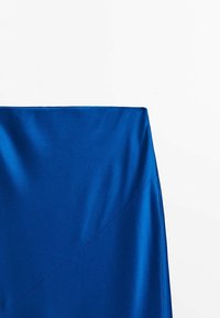 Satiininen sininen hame, jossa on jämäkkä vyötärönauha, vinomaiset saumat ja sileä, kiiltävä pinta.