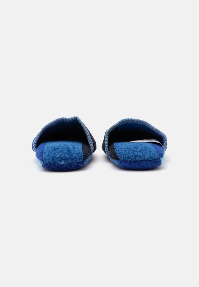 Paar blau-schwarze karierte Hausschuhe mit offenem Fersenbereich, von vorne auf weißem Hintergrund gesehen.