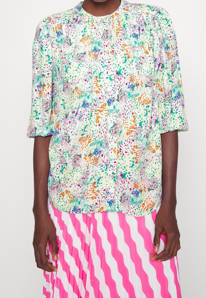 Blouse à motif floral en vert clair avec des couleurs vives, présentant un col rond, des manches trois-quarts et une coupe décontractée.