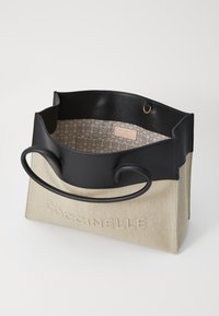 Borsa a tracolla in tela e pelle, corpo beige con dettagli in pelle nera, manici curvi, motivo interno discreto, logo inciso sul davanti.
