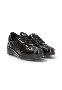 Par de zapatos de mujer negros y brillantes con cordones, con patrones texturizados y suelas gruesas sobre un fondo blanco.