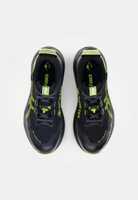 Black and neon green athletic shoes with a textured surface, featuring a GORE-TEX label, lace closure, and curved soles.