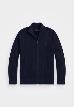 Cardigan en maille bleu marine zippé avec col montant, poches latérales et petit logo brodé sur la poitrine gauche.