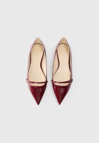 Tacones puntiagudos de charol burdeos con un diseño elegante, que presentan una correa estrecha en el empeine y una plantilla suave en color beige.