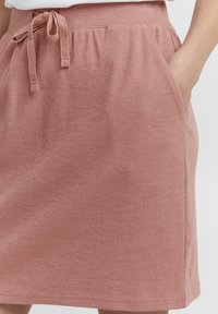 Rosa ribbestrikket skjørt med elastisk midje, justerbar snøring, sidelommer og en glatt tekstur.