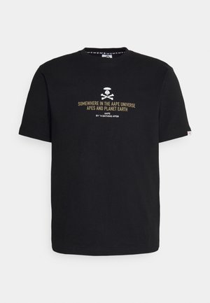 T-shirt en coton noir à manches courtes, ornée d'un design graphique avec une tête de mort et des os croisés, ainsi que du texte en blanc et doré.