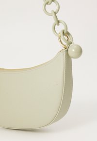 Borsa a tracolla in pelle verde di forma rotonda, con zip dorata e tracolla a catena spessa. Il particolare pomello sulla tracolla aggiunge interesse visivo.