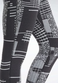Czarne legginsy sportowe z połączeniem geometrycznych i teksturowanych wzorów w odcieniu szarości, z różnorodnymi paskami i kropkowymi motywami w całej powierzchni.