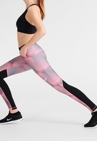 Leggings con un patrón geométrico rosa y gris, acentos negros y un diseño ajustado. El material parece elástico, ideal para ropa atlética.