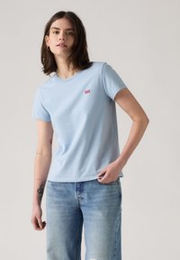 Hele sinine lühikese varrukaga t-särk, mis on valmistatud puuvillast, ja millel on rinnal väike punane logopatch. Lihtne disain ja mugav istuvus.