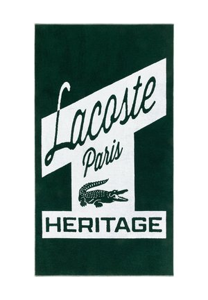 Sfondo verde scuro con un banner diagonale bianco che mostra "Lacoste Paris" in corsivo, il logo del coccodrillo e la scritta "HERITAGE" in lettere maiuscole grassetto.